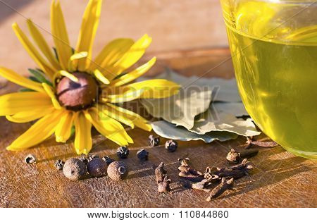 spices black pepper allspice bay leaf flower yellow olive oil wood background