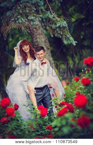 Portrait newlyweds among the blooming roses.