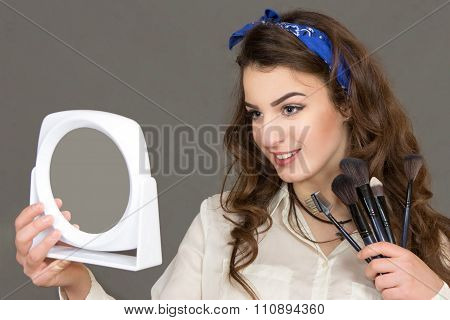 The Beautiful Young Woman Looks In A Mirror