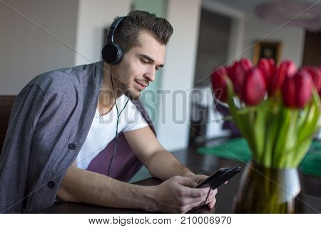 Young casual caucasian man listening music on winter day indoor