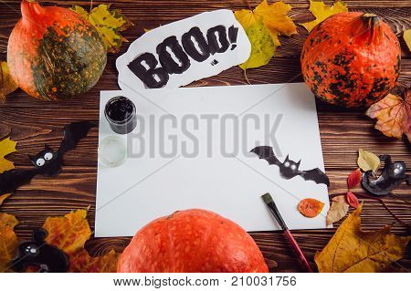Halloween holiday background. Prepearing for party. Fresh pumpkins, coloured leaves, art, craft and painting materials on dark wooden table. Selective focus, top view. Space for text.