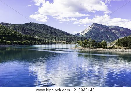 Wooded shore of the lake in French Alps. Lake Castillon is a reservoir in Alpes-de-Haute-Provence in France.