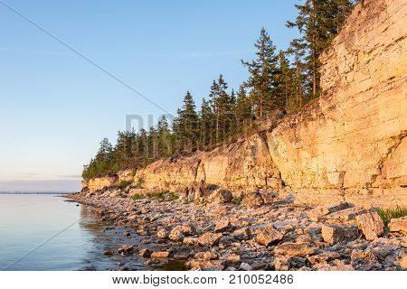 Sunset on the beach. Limestone cliff in the sea under blue sky and white clouds. Kesselaid a small island in Estonia. Nordic countries Europe