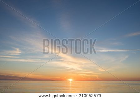 Evening sunlight on coast pink clouds blue sky reflection on water. Beach in summer. Seaside natural environment. Shore in Kesselaid small island in Estonia. Nature Reserve in North Europe