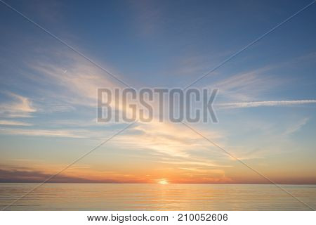 Evening sunlight on coast pink clouds blue sky reflection on water. Beach in summer. Seaside natural environment. Shore in Kesselaid small island in Estonia. Nature Reserve in North Europe