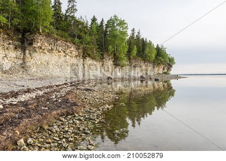 Sunset on the beach. Limestone cliff in the sea under blue sky and white clouds. Kesselaid a small island in Estonia. Nordic countries Europe