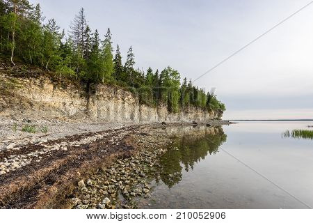 Sunset on the beach. Limestone cliff in the sea under blue sky and white clouds. Kesselaid a small island in Estonia. Nordic countries Europe