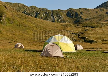 one patient and three small dome tents in the mountain valley