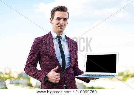 Serious Businessman In Red Suit And Shirt With Tie Stand On The Roof With Laptop