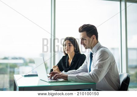 Business People Having Meeting Around Table In Modern Office Against Windows.