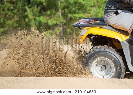 An Atv Quadbike Get Stuck In A Sandy Road Near Forest And Having Wheel-spin Making A Spray Of Sand