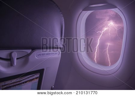Ligthning storm viewed from inside an airplane windows.Airplane flight during a thunderstorm and rain bad weather