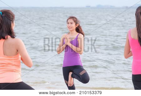 female asia yoga doing tree pose and namaste with calm relax emotion at beachSport training class groupMeditation poseWellness and Healthy Lifestyle.