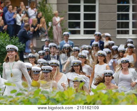 Stockholm Sweden - Jun 13 2017: Happy Teenagers Wearing Graduation Caps Running Out From School Afte
