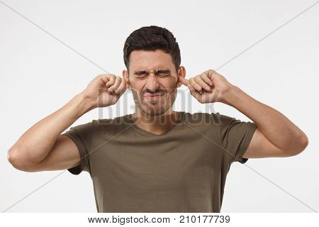 Stressed Frustrated Young Man Plugging His Ears With Fingers And Keeping Eyes Closed While Having He