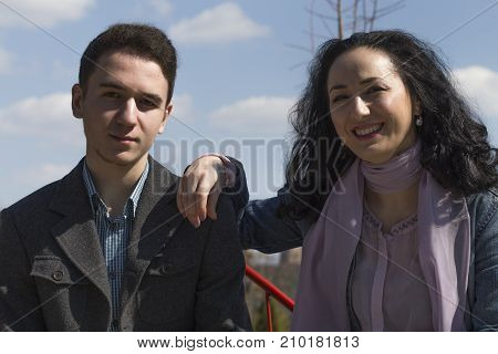 Mother and son are together. Couple sitting on a banch in the park.