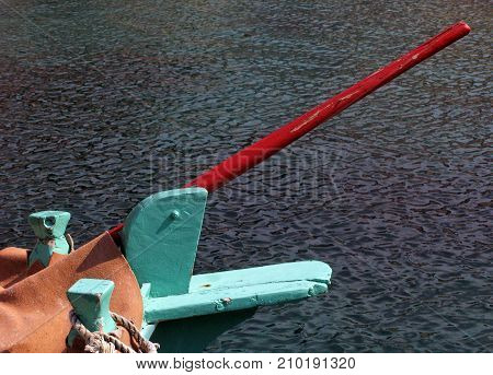 A small green painted wooden fishing boat with red paddle
