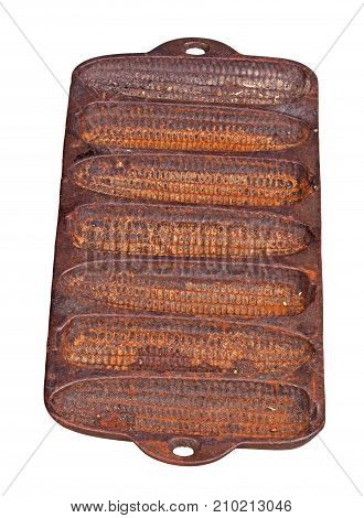 Old rusty cast-iron pan for baking cornbread sticks in the shape of corn on the cob isolated against a white background vertical