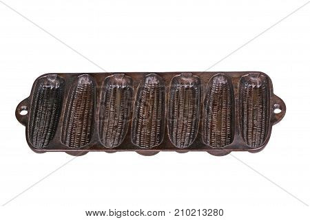 Old but seasoned cast-iron pan ready for baking cornbread sticks in the shape of corn on the cob isolated against a white background