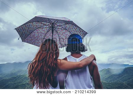 Lover women and men asians travel relax in the holiday. stood in rain umbrellas on the mountain. During the rainy season.Thailand