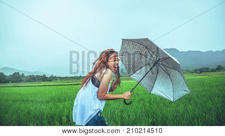 Asian women travel relax in the holiday. Women stand in rain umbrellas. On the meadow During the rainy season.Thailand