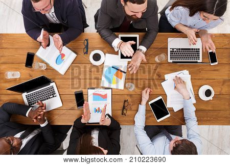 Multiethnic business team in office. Employees clapping hands cheering successful reporter top view of wooden table