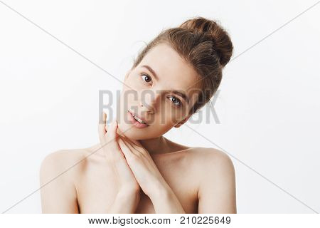 Good-looking relaxed sexy europian student girl holding hands under face, looking in camera with calm face expression, posing for spa avertisment. Copy space