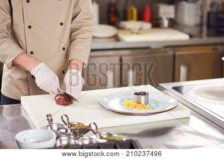 Chef is cutting fried duck breast. Cook at restaurant kitchen preparing dish with poultry meat. Chef cooking delicious food.