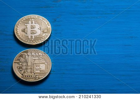 Golden bitcoins on a textured blue wooden background. The concept of virtual business and currency.