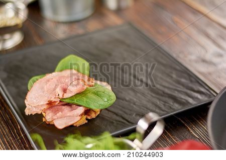 Benedict with ham and basil. Juicy benedict with fresh ham and basil on black board. Restauraunt food and cuisine.