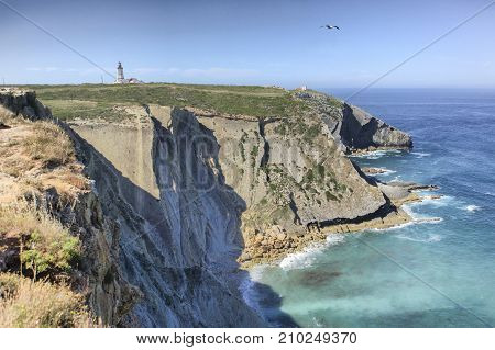 Espichel Cape lighthouse building over rocky cliffs Sesimbra Portugal
