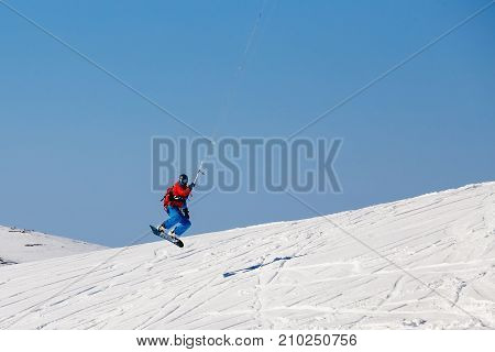 Snowboarder with a kite on fresh snow in the winter in the tundra of Russia against a clear blue sky. Teriberka, Kola Peninsula, Russia. Concept of winter sports snowkite.