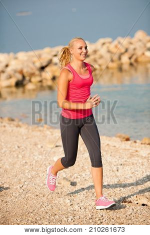 jogging in th beach - woman runns near sea on early summer morning