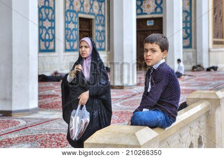 Fars Province Shiraz Iran - 19 april 2017: Shah Cheragh Shrine Muslim woman wearing an Islamic veil passes by one of the unknown boy about 10 years old.