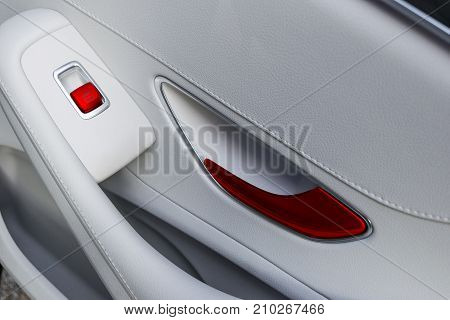 Car white leather interior details of door handle with windows controls and adjustments. Car window controls of modern car.
