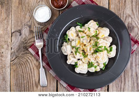 Black plate with boiled vegetarian vegetable dumplings. Studio Photo