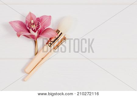 Decorative flat lay composition with makeup products and flowers. Flat lay, top view on white background. Copytext