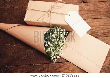 gift in package with bouquet of chamomiles wrapped in paper