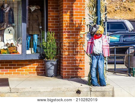 Holiday Scarecrow Displayed On Corner Of Small Town Street