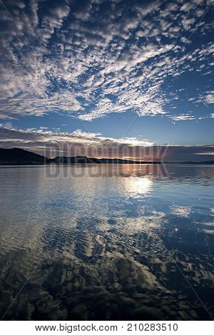 A striking inspirational blue sky cloudy salt water lake sunrise with cloud water reflections. Captured on Lake Macquarie New South Wales Australia