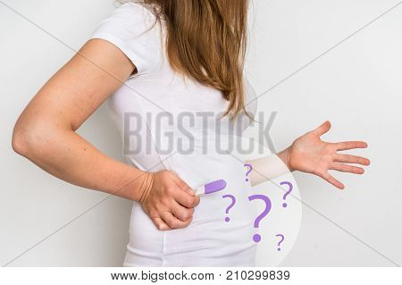 Unhappy woman with imagination of a pregnant belly holding negative pregnancy test - infertility concept