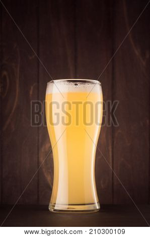Beer glass with muddy weizen on dark wood board vertical. Template for advertising design branding identity restaurant menu cover.