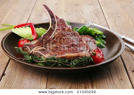 cibo di carne: manzo alla griglia di ricambio rib sul piatto scuro con pepe timo e pomodoro sul tavolo di legno