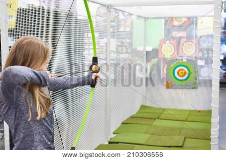 girl shoots a bow in a children's shooting range