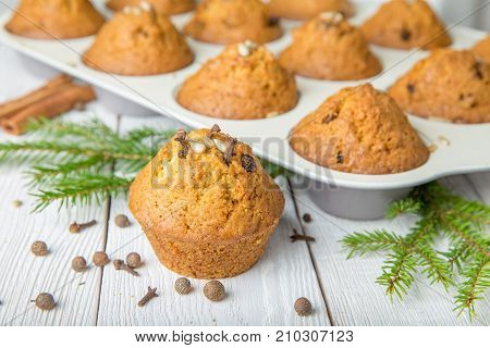 Christmas cupcakes with spices cloves, seeds and nuts in a baking dish on white wooden table