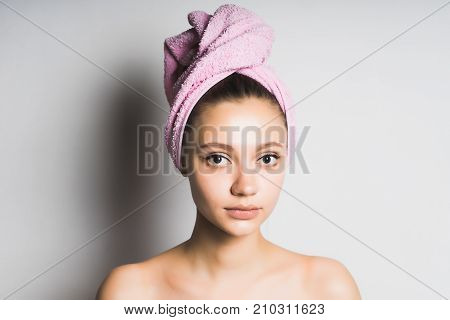 girl after shower with a pink towel on her head watching the camera. Isolated on white background