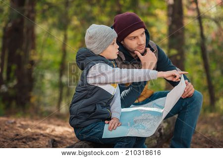 Father And Son With Map In Forest