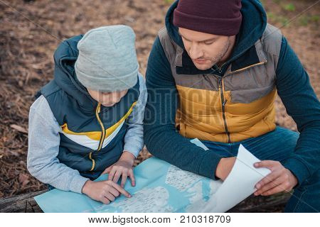 Father And Son With Map In Forest
