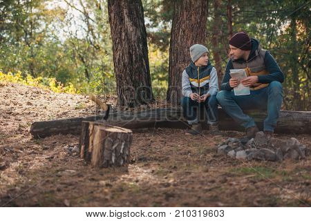 Father And Son With Map In Forest