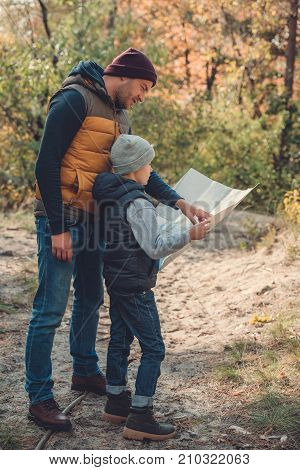 Father And Son With Map In Forest
